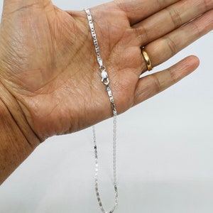 Puede incluir: Un collar de cadena de plata con un dise&ntilde;o de cadena de caja. La cadena est&aacute; en una mano, y el cierre es visible.