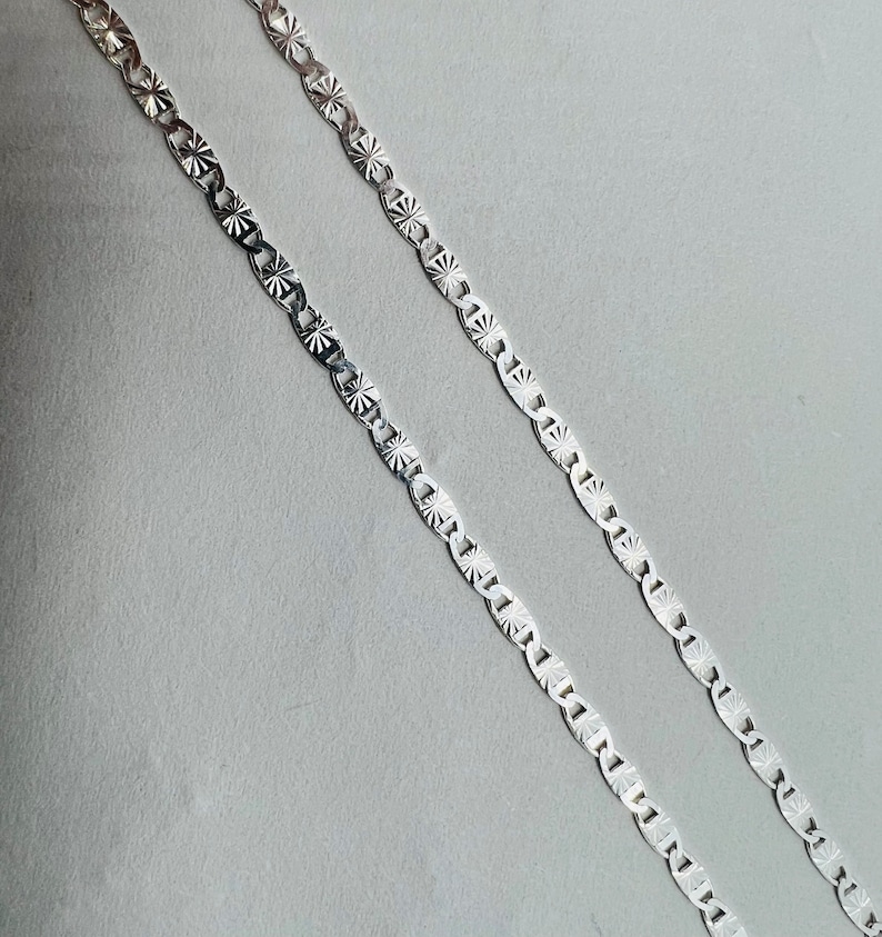Puede incluir: Dos cadenas de plata con un patr&oacute;n de estrella en cada eslab&oacute;n.