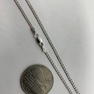 May include: A silver curb chain necklace with a lobster clasp. The chain is laid out on a white surface next to a US quarter.