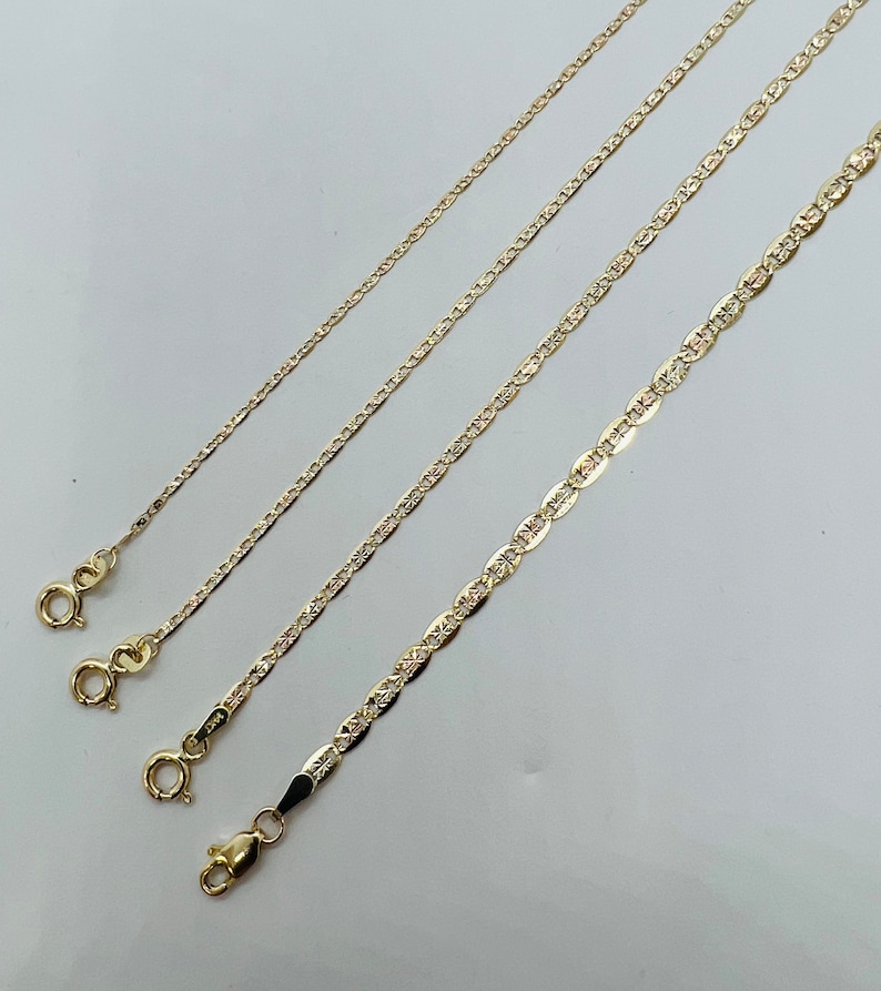 May include: Four gold-coloured necklaces with varying chain styles are shown against a light background. Each chain has a clasp at the end. The chains differ in thickness and design, showcasing a range of jewellery options.