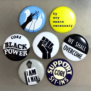 May include: Seven round buttons with various slogans and images related to the Civil Rights Movement. The buttons feature slogans such as "Black Power", "We Shall Overcome", "Support CORE Sit-Ins", and "I Am A Man". One button features a raised fist, another a dove, and another a man holding a sign.