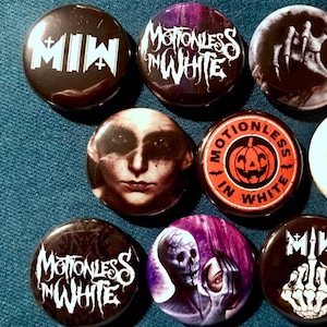 Puede incluir: Nueve pines de botón negros y blancos con varios diseños que presentan a la banda Motionless In White. Los pines muestran el nombre de la banda, una calavera, una calabaza y una mano.