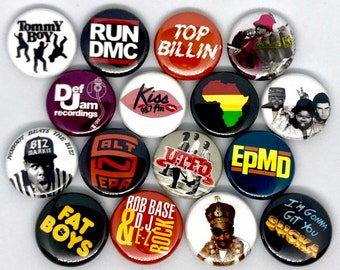 May include: A collection of 15 round buttons featuring various hip hop artists and groups, including Run DMC, Salt-N-Pepa, Biz Markie, and UTFO. The buttons are black, red, white, and yellow.
