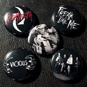 May include: Five black and white button pins with different designs. The pins feature the text "Freak Like Me", "Vicious", "Halestorm", and two images.