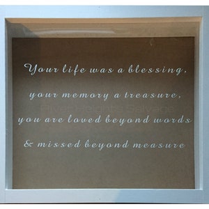 May include: White framed shadow box with a brown background and white text that reads "Your life was a blessing, your memory a treasure, you are loved beyond words & missed beyond measure".