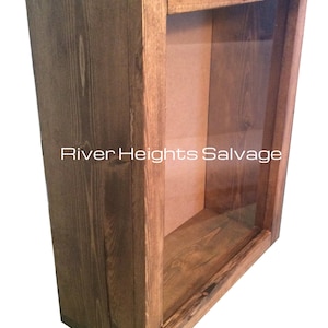 May include: A rustic wooden shadow box with a glass front. The box is stained a dark brown color and has a simple design. The text "River Heights Salvage" is visible on the glass.
