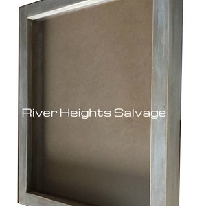 May include: A grey wooden shadow box with a clear glass front. The box is made from reclaimed wood and has a rustic look. The text "River Heights Salvage" is visible on the front of the box.