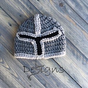 Puede incluir: Un gorro de punto de color gris y negro con forma de casco de caballero. El gorro tiene una visera negra y un patr&oacute;n gris y blanco.