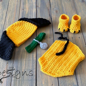 Puede incluir: Un conjunto de bebé de ganchillo en amarillo y negro, que incluye un gorro, un body y botines. El conjunto está diseñado para parecer un perro.