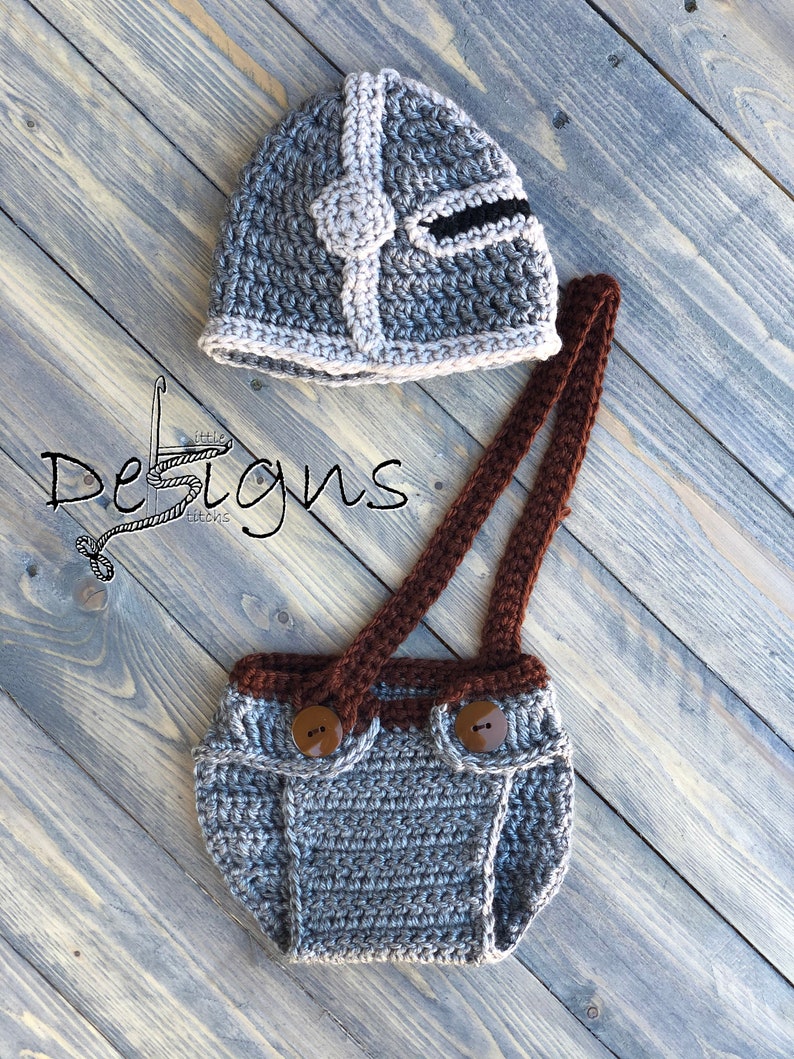 Puede incluir: Sombrero de beb&eacute; de ganchillo gris con dise&ntilde;o de casco y cubrepa&ntilde;al de ganchillo gris a juego con tirantes y botones marrones.