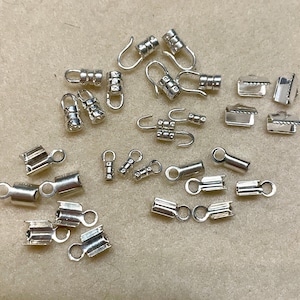 May include: A collection of silver-toned metal jewelry findings, including clasps, end caps, and jump rings. These findings are perfect for creating necklaces, bracelets, and other jewelry pieces.