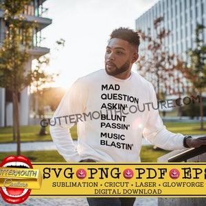 May include: A white long-sleeve shirt with black text that reads "MAD QUESTION ASKIN' BLUNT PASSIN' MUSIC BLASTIN'". The shirt is worn by a person standing in front of a building.