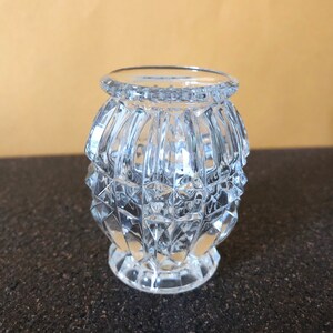 May include: A clear glass vase with a diamond pattern. The vase is round and has a wide mouth.