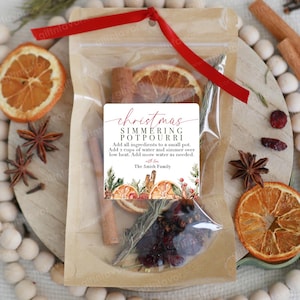 May include: A clear and brown pouch containing Christmas simmering potpourri with dried orange slices, cinnamon sticks, and spices. A red ribbon is tied at the top. The label reads: Christmas Simmering Potpourri, instructions, and The Smith Family.