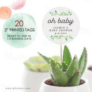 Puede incluir: Veinte etiquetas redondas blancas impresas de 5 cm de di&aacute;metro con follaje verde y el texto "oh baby" en negro. El texto "Jasmin's Baby Shower 9.21.2021" tambi&eacute;n est&aacute; impreso en negro. Las etiquetas est&aacute;n sujetas a brochetas de madera y colocadas en peque&ntilde;as macetas de plantas.