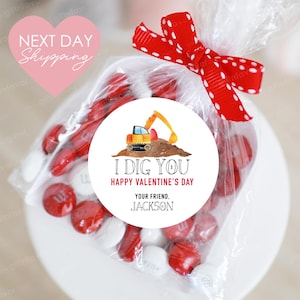 May include: A white circle sticker with a yellow excavator digging in the dirt. The sticker says "I Dig You Happy Valentine's Day Your Friend. Jackson".