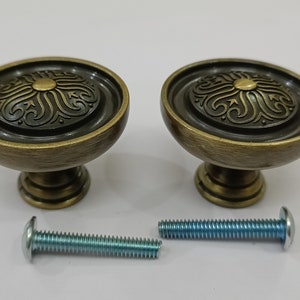 Pu&ograve; includere: Due pomelli per mobili in oro antico con un design floreale decorativo e una vite abbinata.