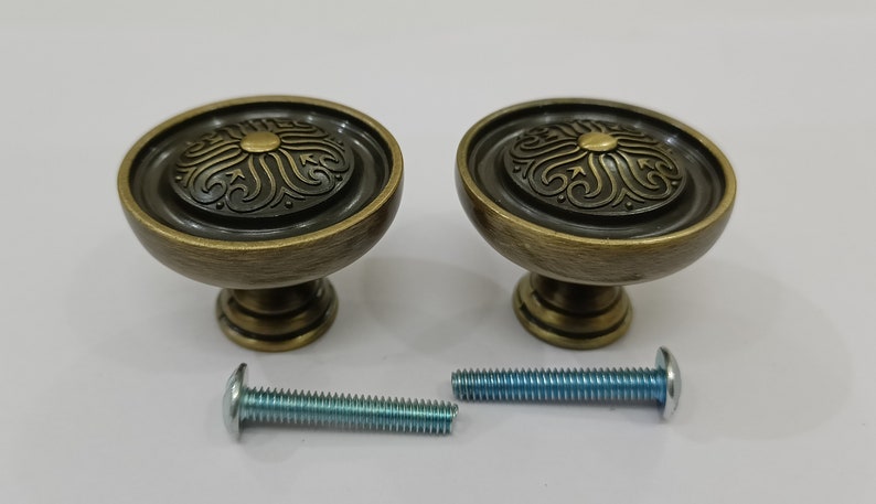 Pu&ograve; includere: Due pomelli per mobili in oro antico con un design floreale decorativo e una vite abbinata.