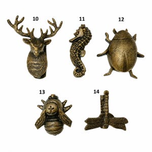 Puede incluir: Un conjunto de cinco pomos de metal en tono lat&oacute;n antiguo con formas de animales e insectos. El set incluye una cabeza de ciervo numerada 10, un caballito de mar 11, un escarabajo 12, una abeja 13 y una lib&eacute;lula numerada 14.