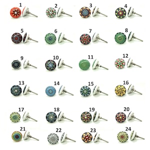 Puede incluir: Una colección de 24 pomos decorativos para armarios con diseños coloridos y estampados. Cada pomo presenta una cara redonda pintada con una variedad de patrones de puntos en colores como rojo, verde, azul y amarillo. Los pomos tienen una base blanca y un vástago de metal plateado.