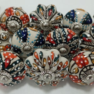May include: A collection of 12 ceramic drawer knobs with a white base and colorful floral patterns. The knobs have a silver metal base and are perfect for adding a touch of vintage charm to any home.