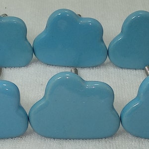 Pode incluir: Dez puxadores de arm&aacute;rio em forma de nuvem azul claro com hastes prateadas. Os puxadores est&atilde;o dispostos em duas fileiras de cinco, oferecendo um toque l&uacute;dico para m&oacute;veis ou decora&ccedil;&atilde;o. Os puxadores s&atilde;o feitos de cer&acirc;mica.