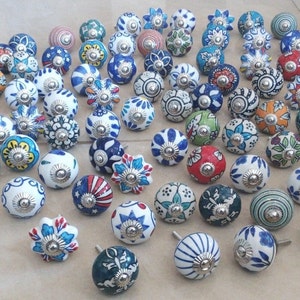 May include: A collection of 50 ceramic cabinet knobs featuring a variety of colourful floral patterns. The knobs are white with blue, green, red, and yellow accents. Each knob has a silver metal base.