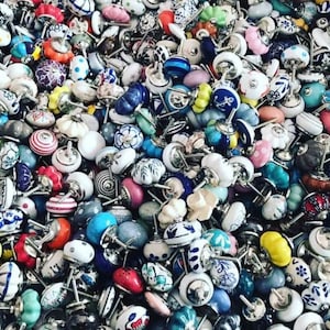 May include: A large collection of colourful ceramic cabinet knobs with various patterns and designs. The knobs are all different shapes and sizes, and they are arranged in a random pattern.