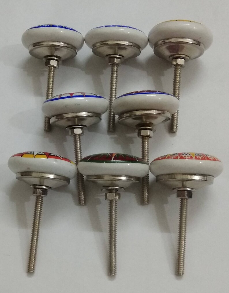 May include: Set of seven ceramic cabinet knobs with colourful floral designs. Each knob has a silver base and a threaded screw.