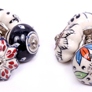 Puede incluir: Surtido de pomos de caj&oacute;n de cer&aacute;mica con varios patrones florales y geom&eacute;tricos en tonos de azul, rojo, blanco y negro.