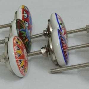 May include: Set of six ceramic cabinet knobs with colourful floral designs and silver metal screws. The knobs are white with red, blue, yellow, and green accents.