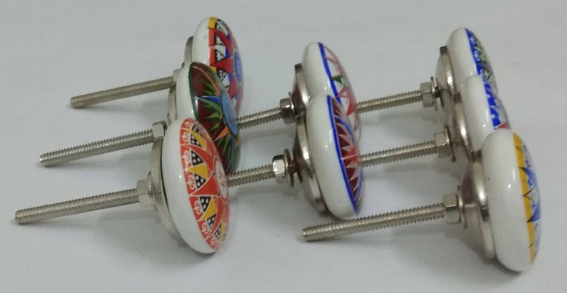 May include: Set of six ceramic cabinet knobs with colourful floral designs and silver metal screws. The knobs are white with red, blue, yellow, and green accents.