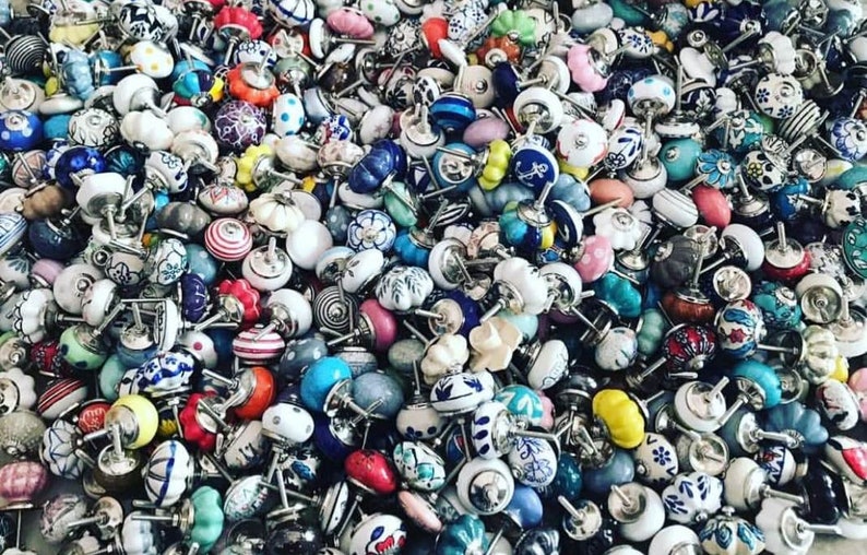 May include: A large collection of colourful ceramic cabinet knobs with various patterns and designs. The knobs are all different shapes and sizes, and they are arranged in a random pattern.