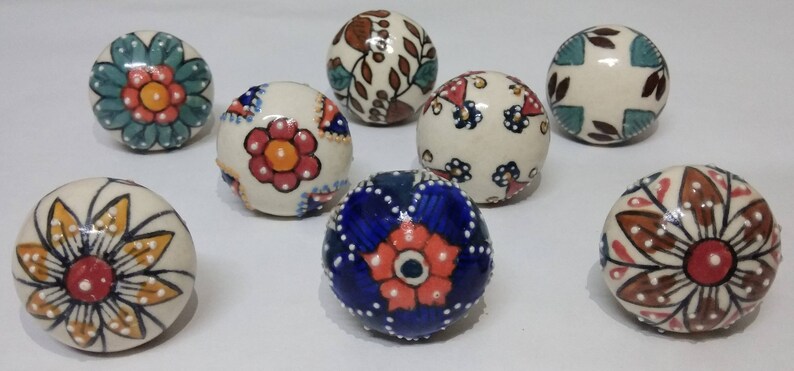 May include: Eight ceramic knobs with colorful floral and geometric patterns. The knobs are round and have a white base with various colors including blue, red, green, brown, and yellow.