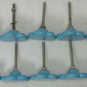 Pode incluir: Seis puxadores de arm&aacute;rio em forma de nuvem azul claro com parafusos e porcas de metal prateado. Os puxadores est&atilde;o dispostos em duas fileiras de tr&ecirc;s, com o desenho da nuvem voltado para cima e para baixo. Para m&oacute;veis.