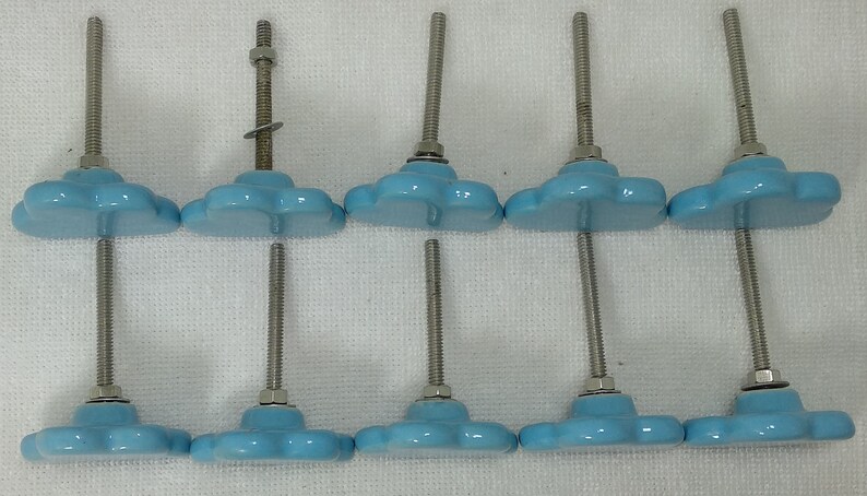 Pode incluir: Seis puxadores de arm&aacute;rio em forma de nuvem azul claro com parafusos e porcas de metal prateado. Os puxadores est&atilde;o dispostos em duas fileiras de tr&ecirc;s, com o desenho da nuvem voltado para cima e para baixo. Para m&oacute;veis.