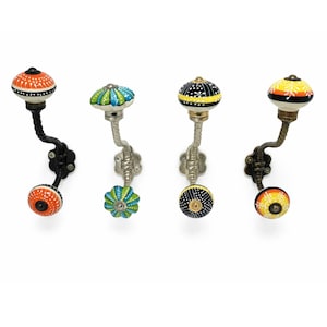 May include: Four decorative wall hooks with colorful ceramic knobs. The knobs feature various patterns in orange, green, yellow, and black. The hooks have metal stems and mounting plates, adding a touch of artistic flair to any space.