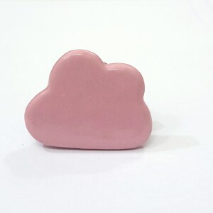 Pu&ograve; includere: Un pomello per cassetti o armadi in ceramica rosa a forma di nuvola.