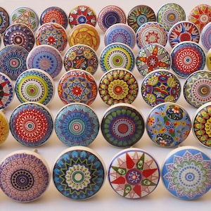 Puede incluir: Una colecci&oacute;n de 36 pomos de caj&oacute;n de cer&aacute;mica coloridos con intrincados dise&ntilde;os de mandalas. Cada pomo presenta un patr&oacute;n &uacute;nico en tonos de azul, rojo, amarillo, verde y blanco.