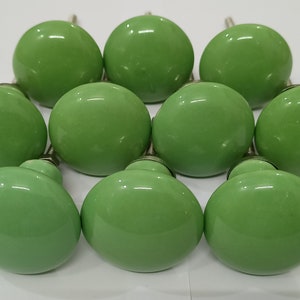 May include: Ten green ceramic cabinet knobs with a shiny finish.