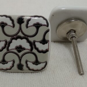 Peut inclure: Bouton de porte carr&eacute; en c&eacute;ramique blanche avec un motif floral noir et blanc. Le bouton est dot&eacute; d'une vis argent&eacute;e.