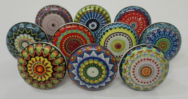 Puede incluir: Surtido de diez pomos de cer&aacute;mica coloridos con dise&ntilde;os de mandalas. Cada pomo presenta un patr&oacute;n diferente de c&iacute;rculos conc&eacute;ntricos, estrellas y formas geom&eacute;tricas en tonos de azul, verde, rojo, amarillo y naranja.