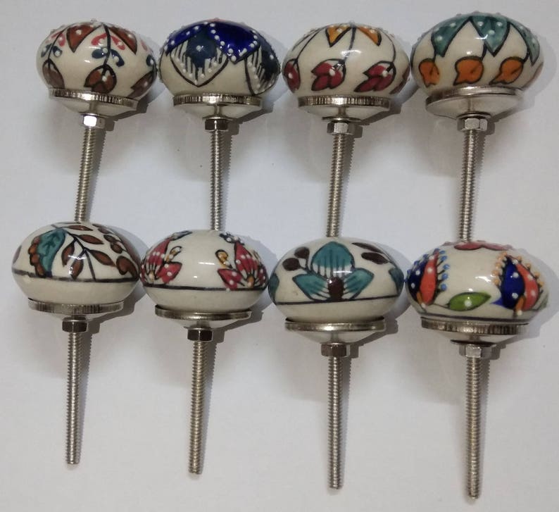 May include: Set of eight ceramic cabinet knobs with colorful floral patterns and silver metal stems.