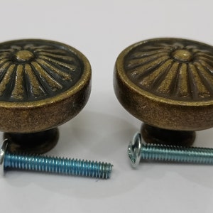 Pu&ograve; includere: Due pomelli per armadi in oro antico con un design a raggiera decorativo e viti abbinate.