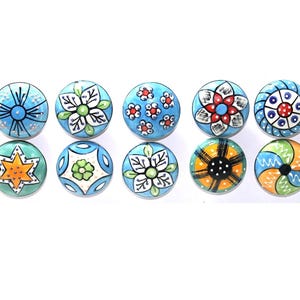 Tiradores de cajón de cerámica de color azul cielo con diferentes diseños y herrajes cromados.