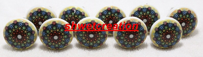 May include: Ten ceramic knobs with a yellow background and a colourful mandala design. The mandala is in shades of blue, green, red, and black.