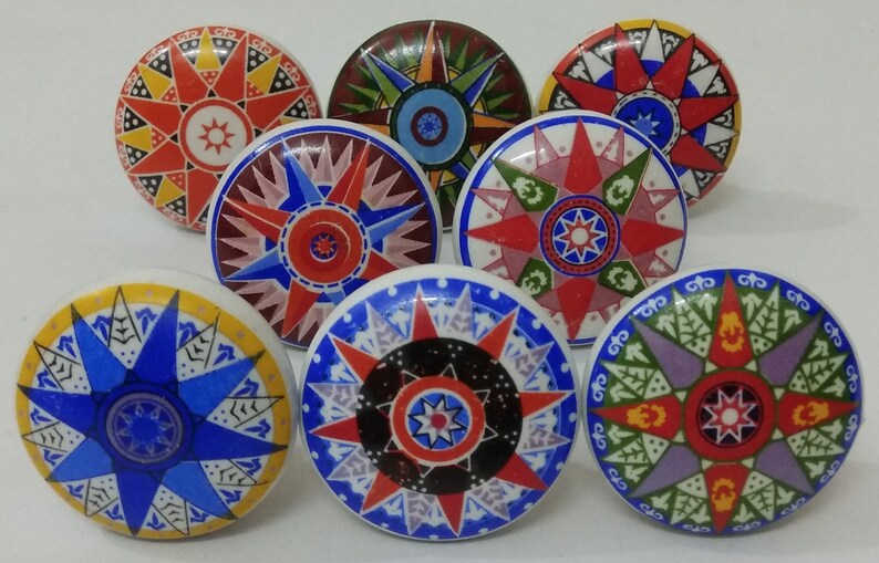May include: Eight ceramic knobs with a starburst design in various colours, including red, blue, yellow, green, and purple. Each knob features a unique pattern within the starburst.