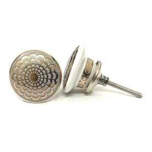 May include: Two decorative cabinet knobs. The knobs feature a floral design in silver and copper tones on a grey background. The knob's base is white with a silver metal screw and hardware.