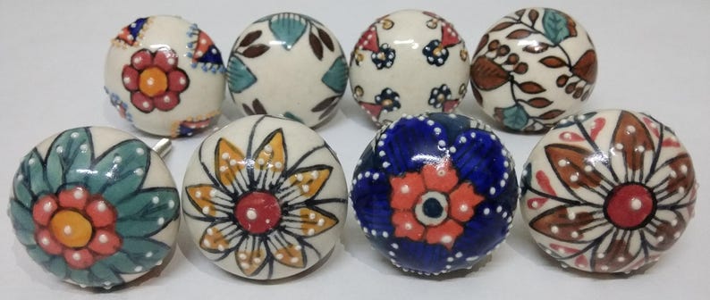 May include: Set of ten ceramic cabinet knobs with colorful floral and geometric patterns. The knobs are round and have a white base with various colors and designs.
