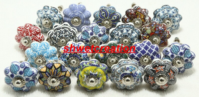 May include: Assortment of 18 ceramic drawer knobs with various floral and geometric patterns in shades of blue, red, green, yellow, and white. Each knob has a silver metal base.